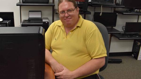 man sitting at desk with computer tower